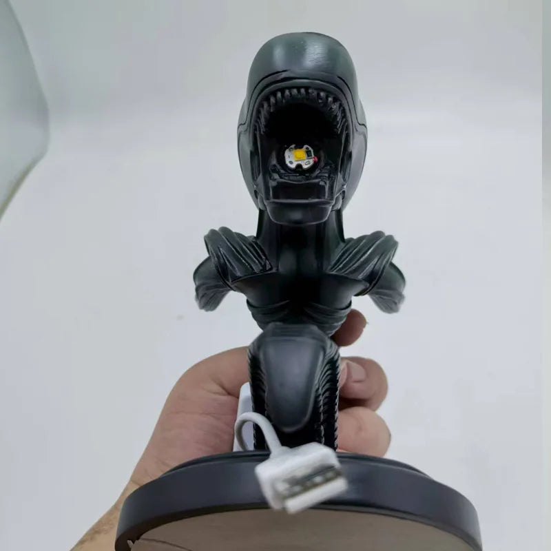 Black robot-like figure held by a hand against a white background - Unique alien creature resin lamp stand for modern home decor