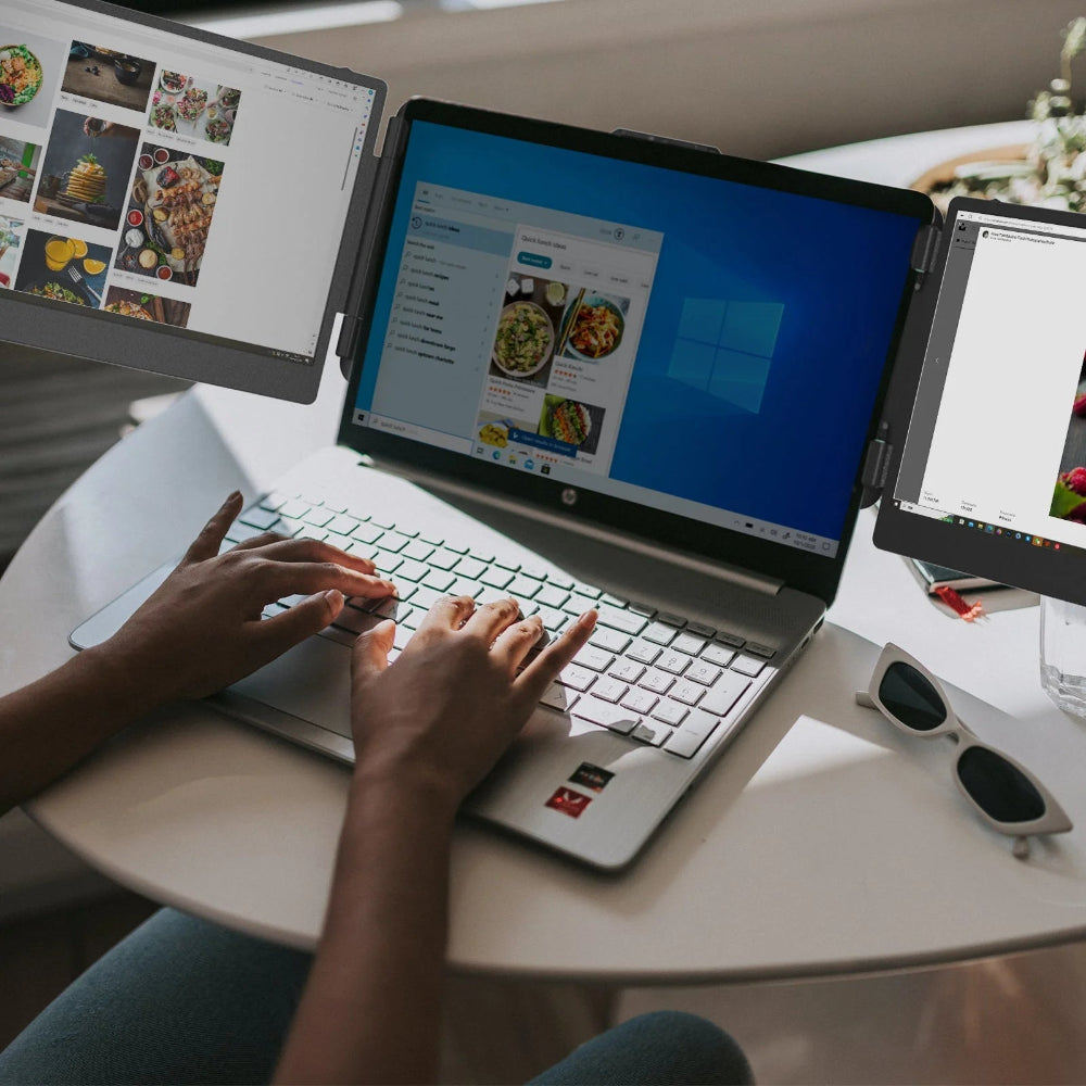 Person using a laptop with multiple screens displaying food images on a table.