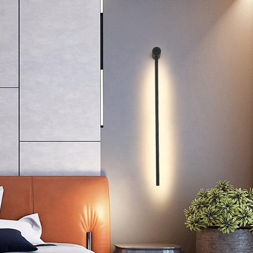 Modern wall-mounted light fixture in a bedroom setting with a bed and plant.