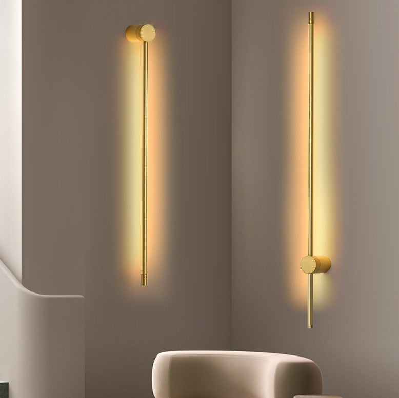 Two modern wall lights on a gray wall with a neutral chair in the foreground.