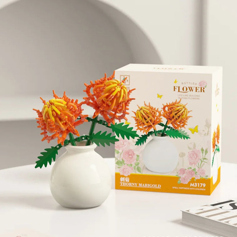 Decorative flower arrangement in a vase next to its packaging on a light surface.