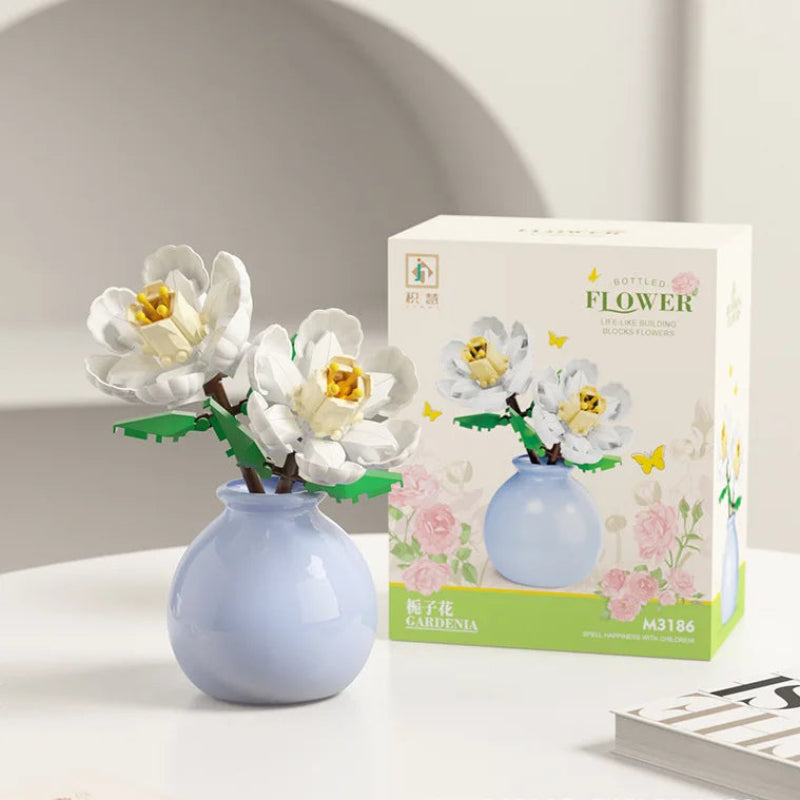 Decorative flower arrangement in a blue vase next to its packaging on a white surface.