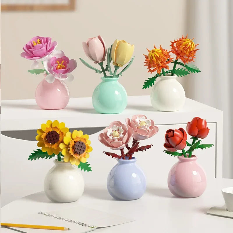 Set of colorful artificial flower arrangements in small vases on a white surface.