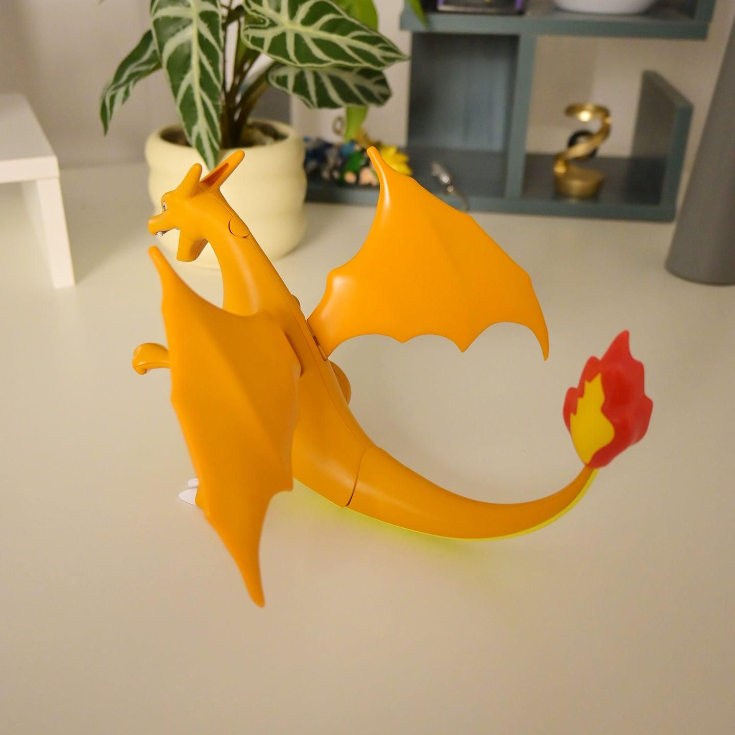 Orange dragon-like toy figure on a light surface with a plant and shelf Interactive dragon figure toy with fire-breathing spray effects and LED lighting