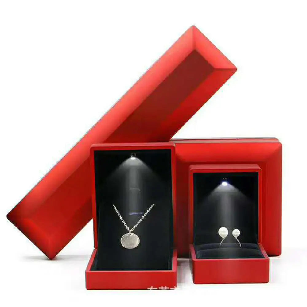 Red jewelry box with a necklace and earrings inside, on a white background