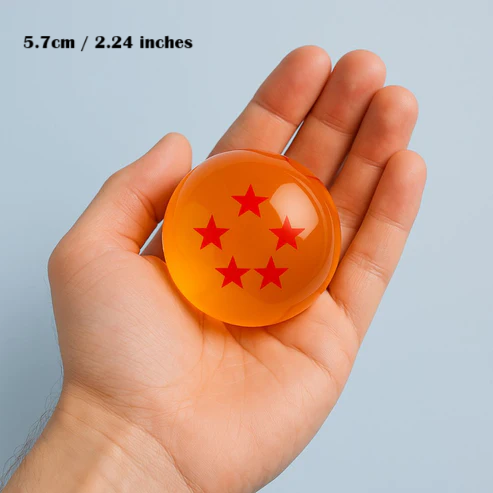 Hand holding a small orange sphere with red star patterns against a light blue background