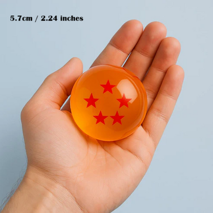 Hand holding a small orange sphere with red star patterns against a light blue background