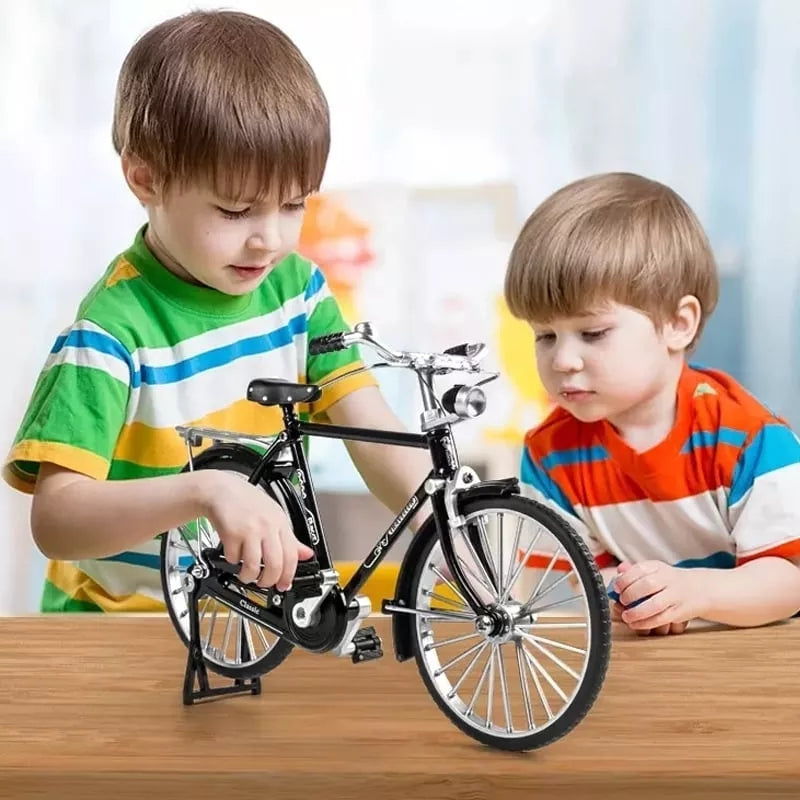 Two children playing with a toy bicycle on a wooden table.