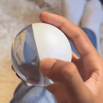 Hand holding a clear crystal ball with a blurred background