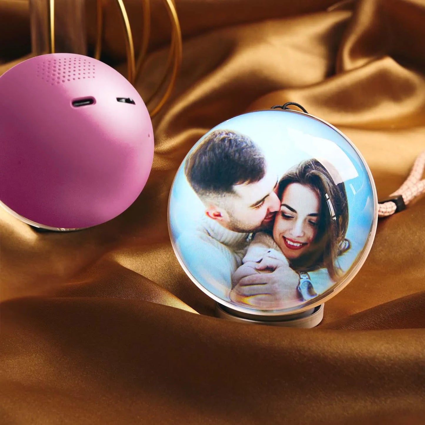 Pink spherical object and a decorative item with a couple's photo on a brown fabric background
