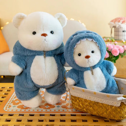 Two teddy bears in blue outfits on a decorative surface with flowers in the background.
