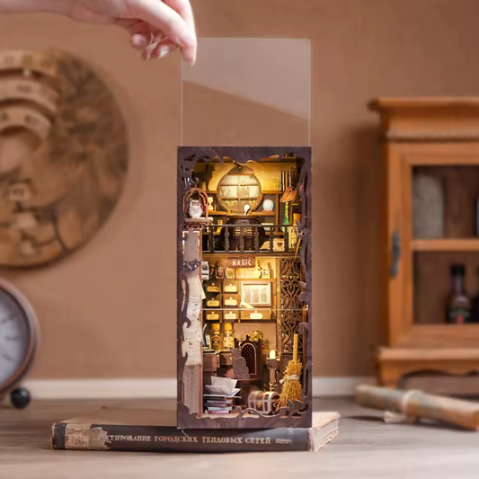 Miniature diorama inside a book with a hand lifting a clear panel, set against a warm-toned interior background.