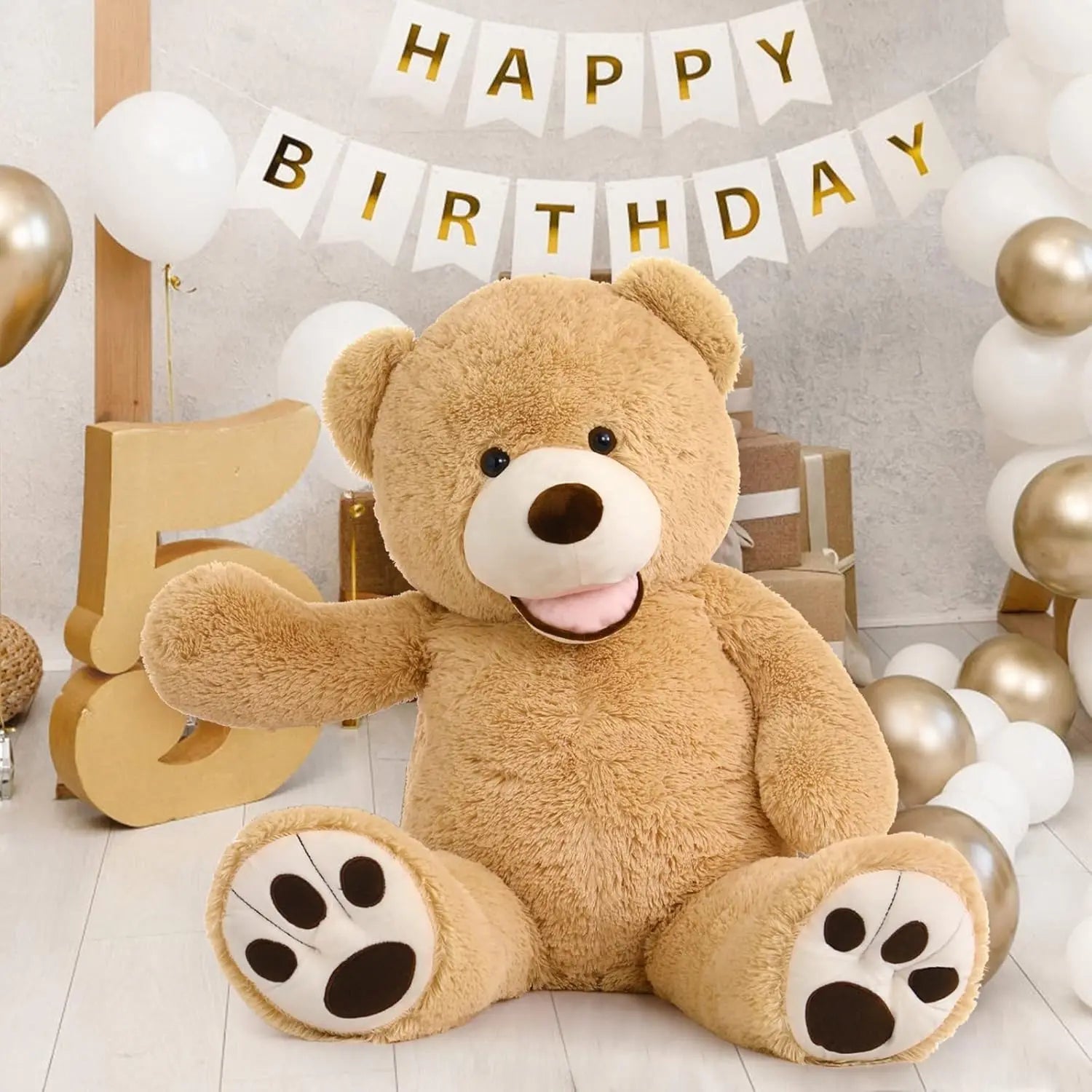 Large teddy bear in a birthday setting with balloons and 'Happy Birthday' banner.