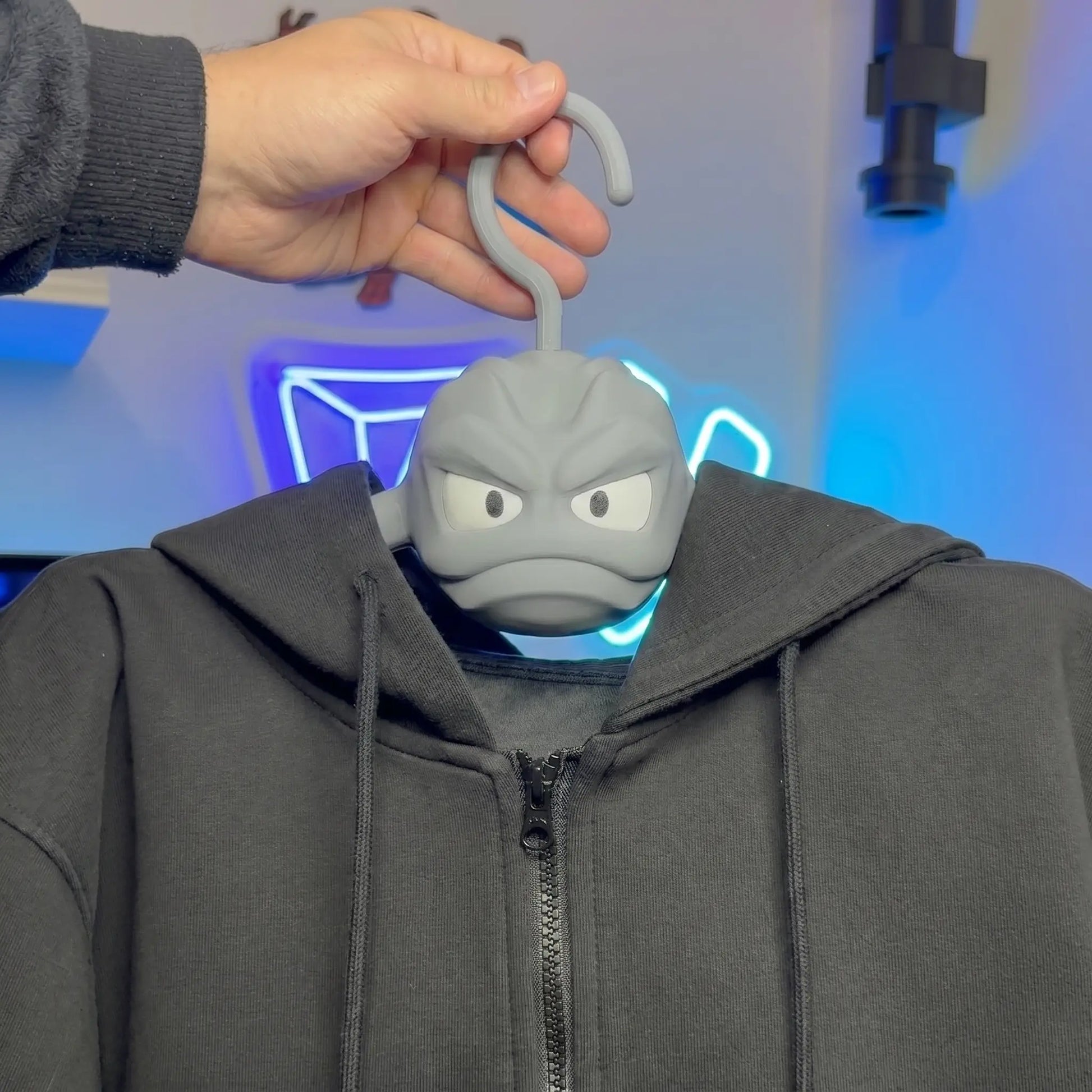 Pokemon Geodude clothes hanger holding a black hoodie above a gamer room desk with neon decor, anime fan room buddy