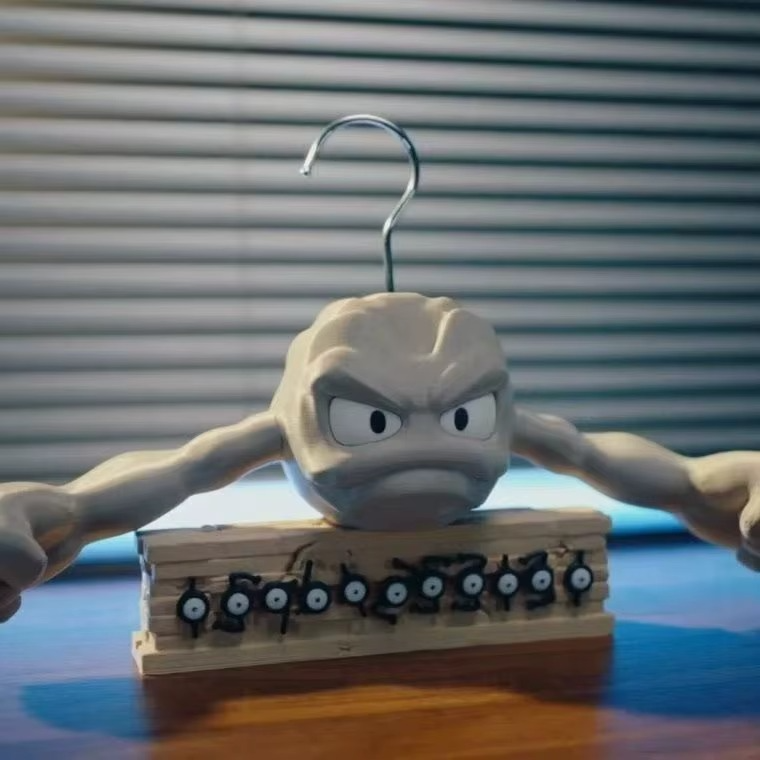 Geodude clothes hanger on a desk display stand with Pokemon figures, collectible novelty coat hanger for fan room decor