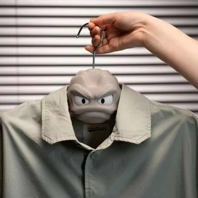 Hand holding the Pokemon Geodude hanger inside a gray jacket collar, anti-slip arms gripping coat for closet rod hanging