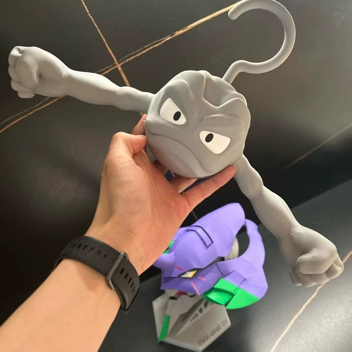 Pokemon Geodude clothes hanger held next to an anime mech figure for scale, rock type novelty coat hanger gift idea
