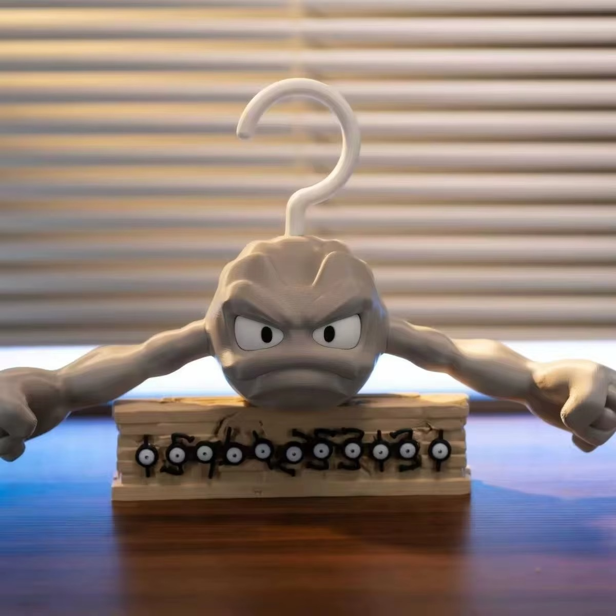 Geodude Pokemon hanger displayed on a desk with collectible anime figurines, gamer room rock monster wardrobe decor