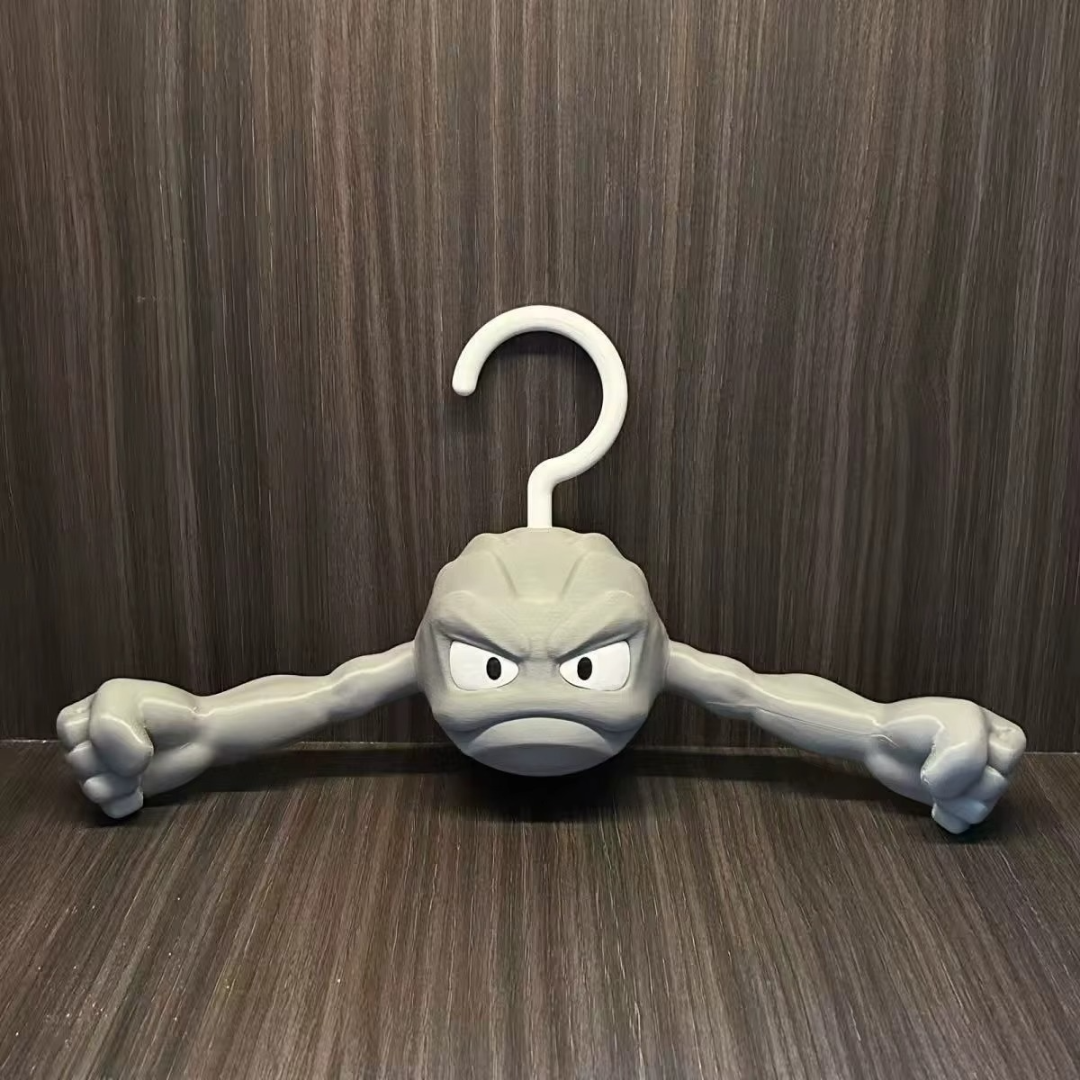 Pokemon Geodude clothes hanger front view on warm wood background, anime rock monster coat hanger for bedroom closet