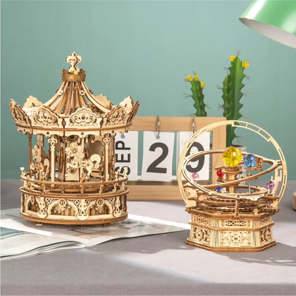 Two wooden mechanical models on a table with a calendar and cactus in the background.