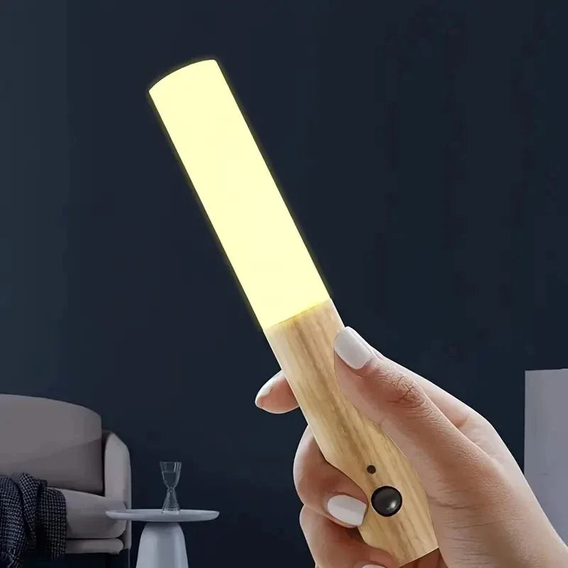 Hand holding a wooden flashlight with a dark background