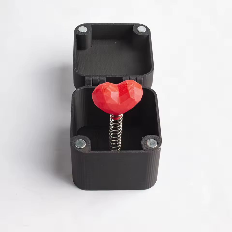 Black box with a red heart-shaped object inside on a white background