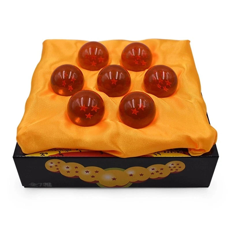 Set of seven red balls with stars on a yellow cloth inside a black box with Dragon Ball Z design.